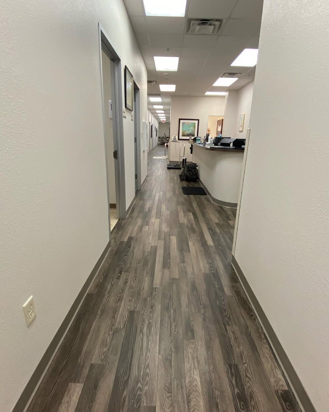 A long hallway with a wooden floor in a hospital.