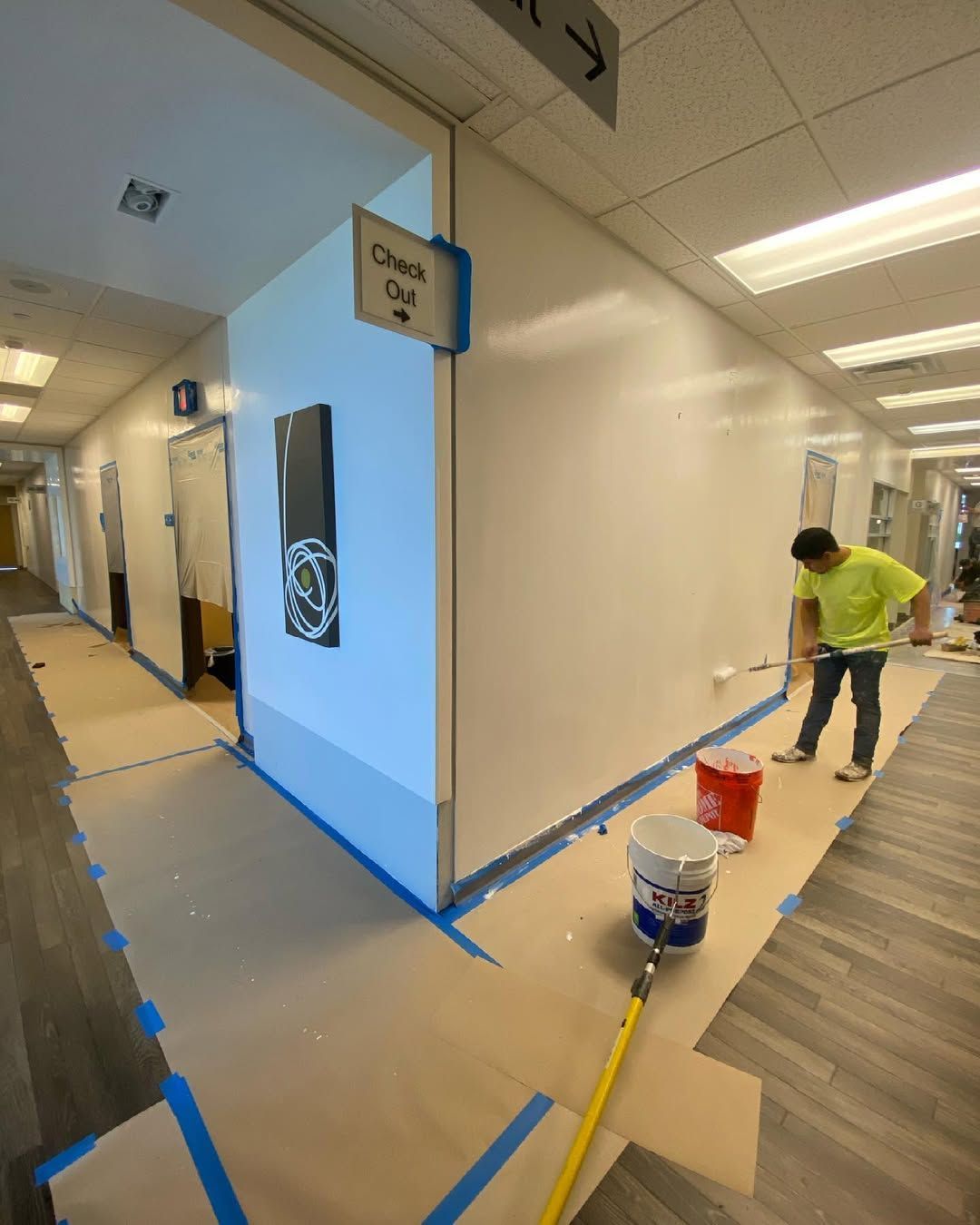 A man is painting a wall in a hallway.