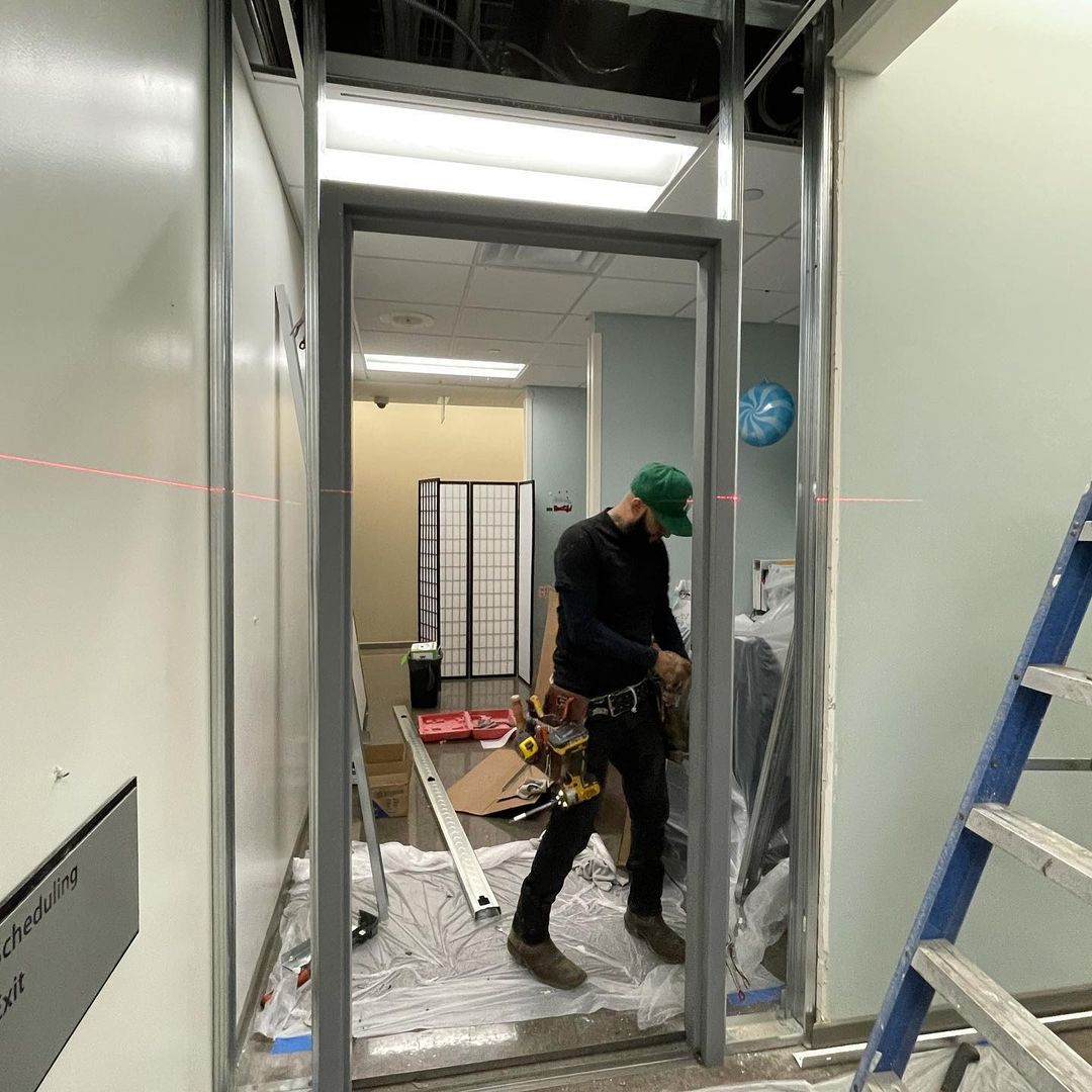 A man is installing a glass door in a building.