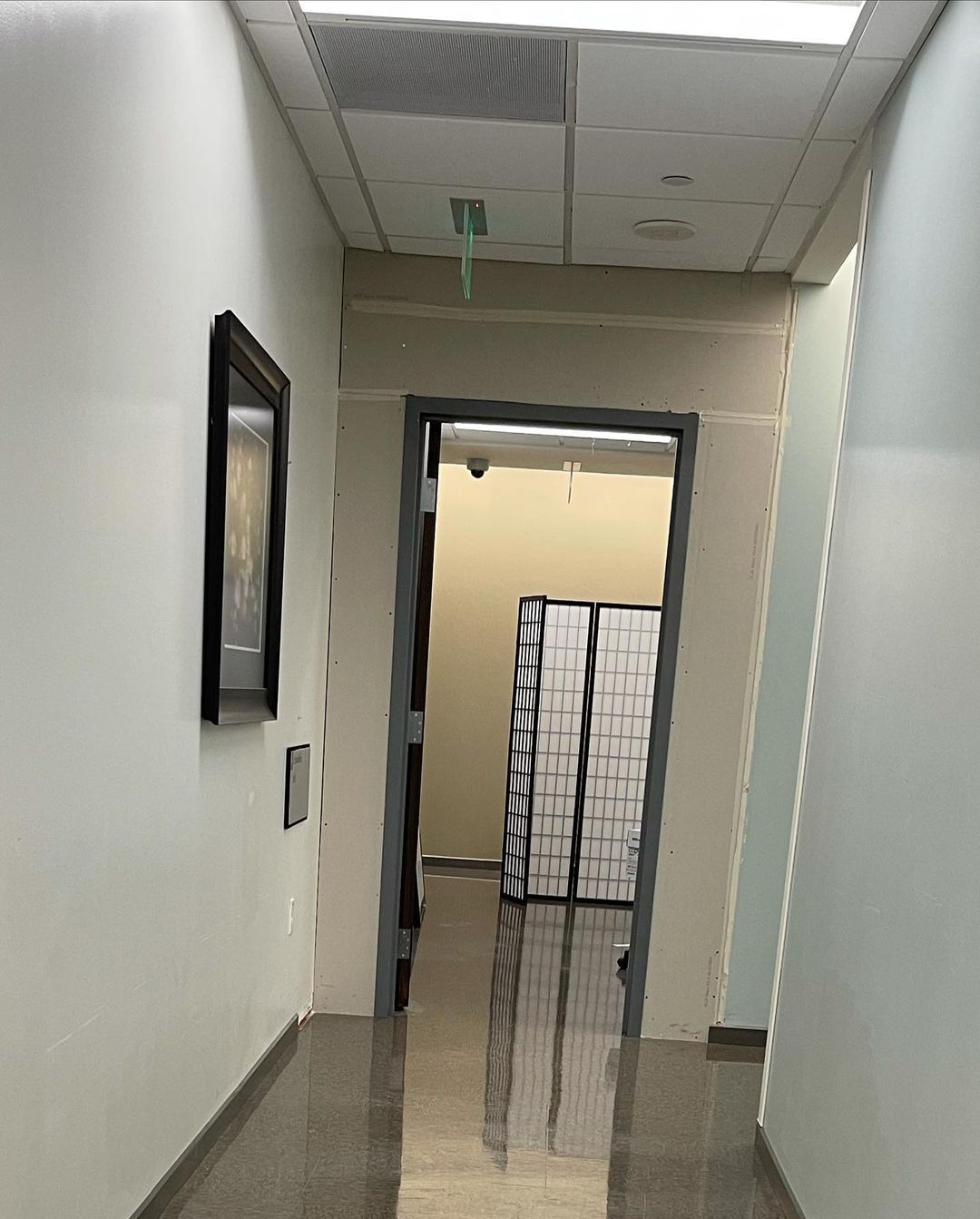 A long hallway with boxes on the floor and a mirror on the wall.