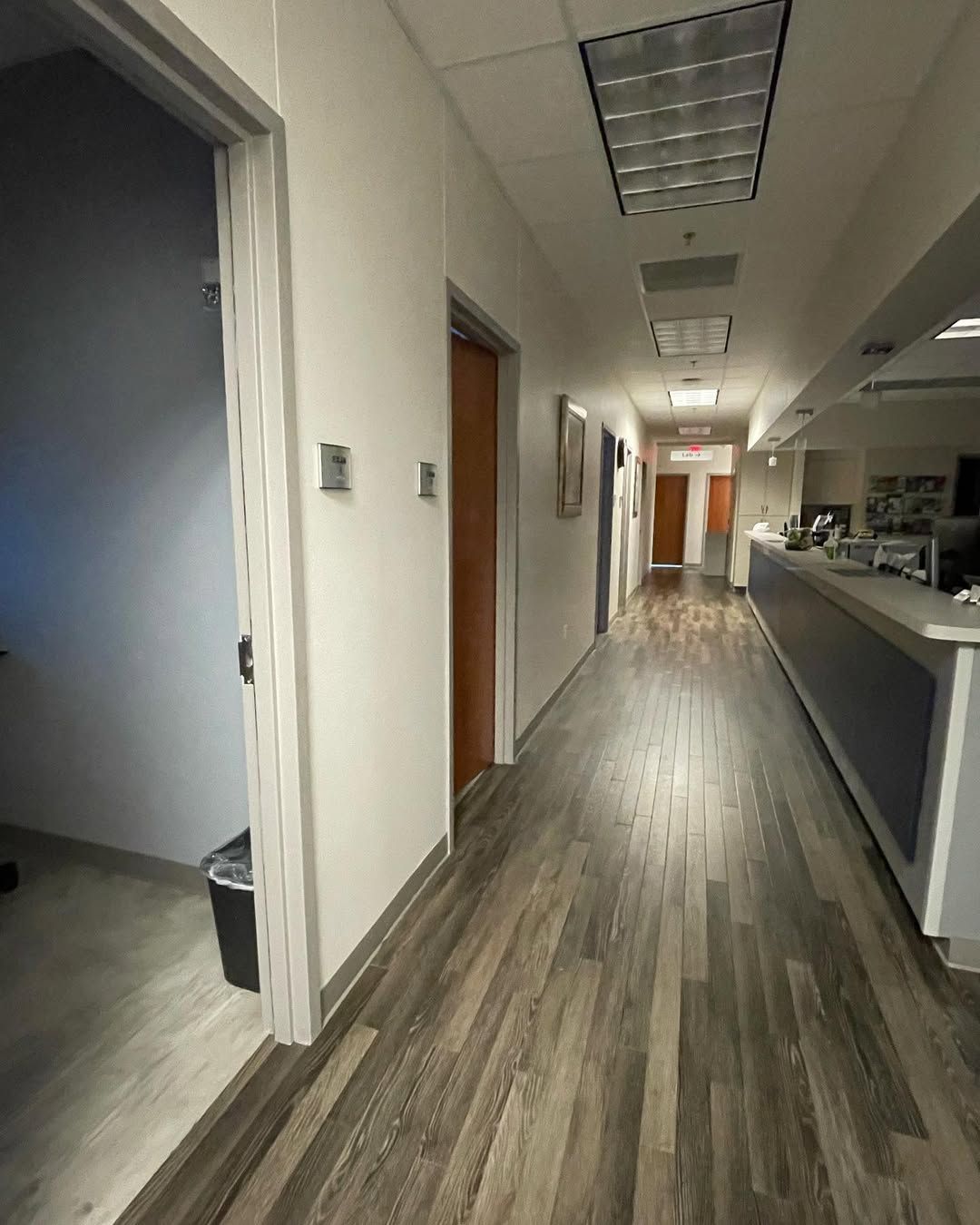 A long hallway with wooden floors in an office building.