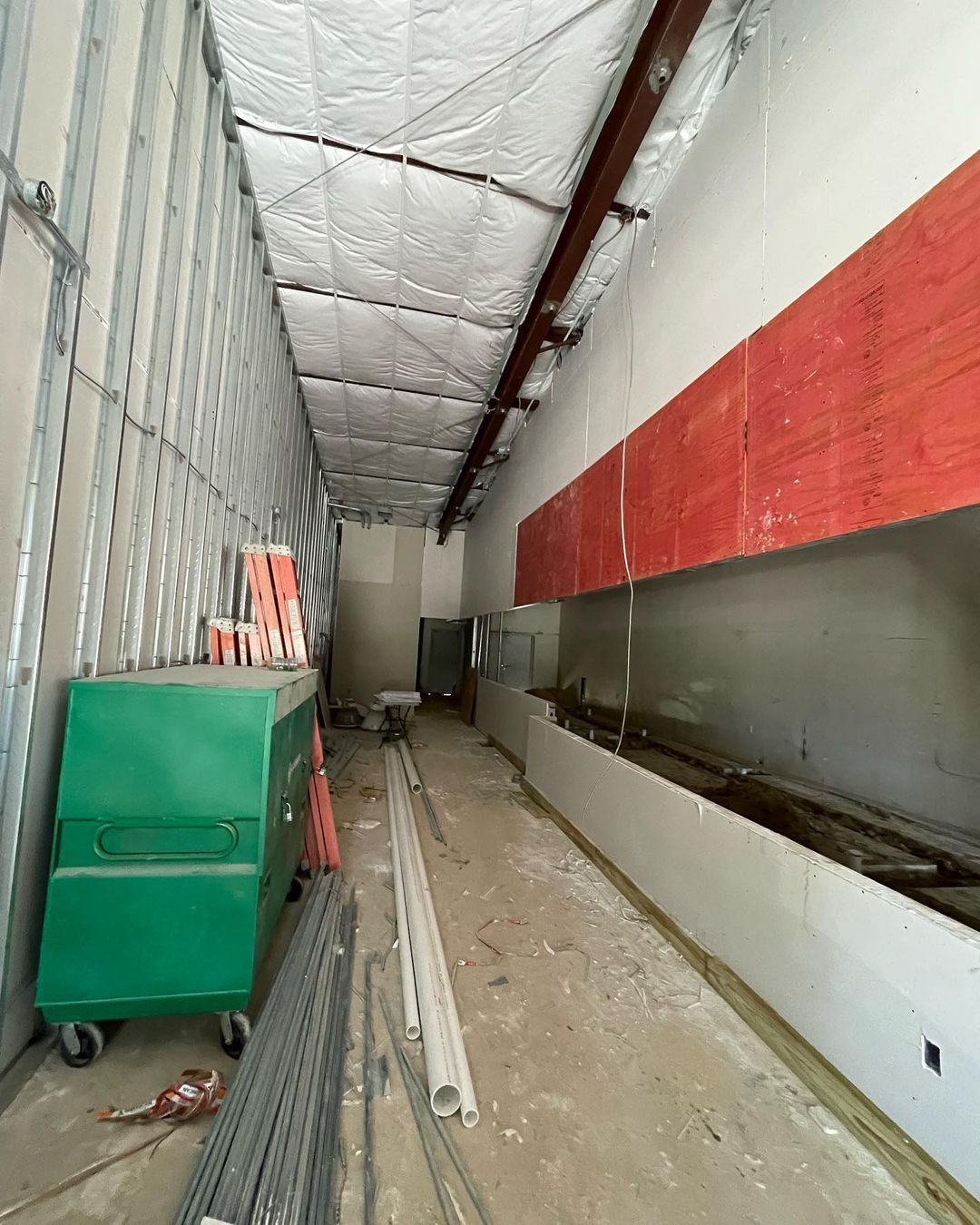 A long hallway with a green cart in the middle of it.