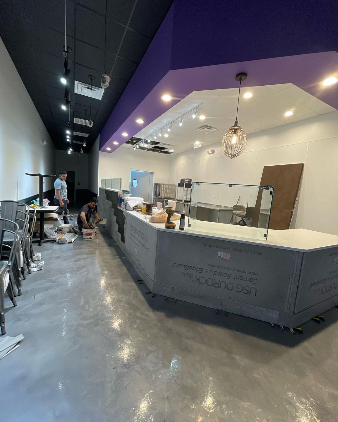 A restaurant is being built with a purple ceiling and a long counter.
