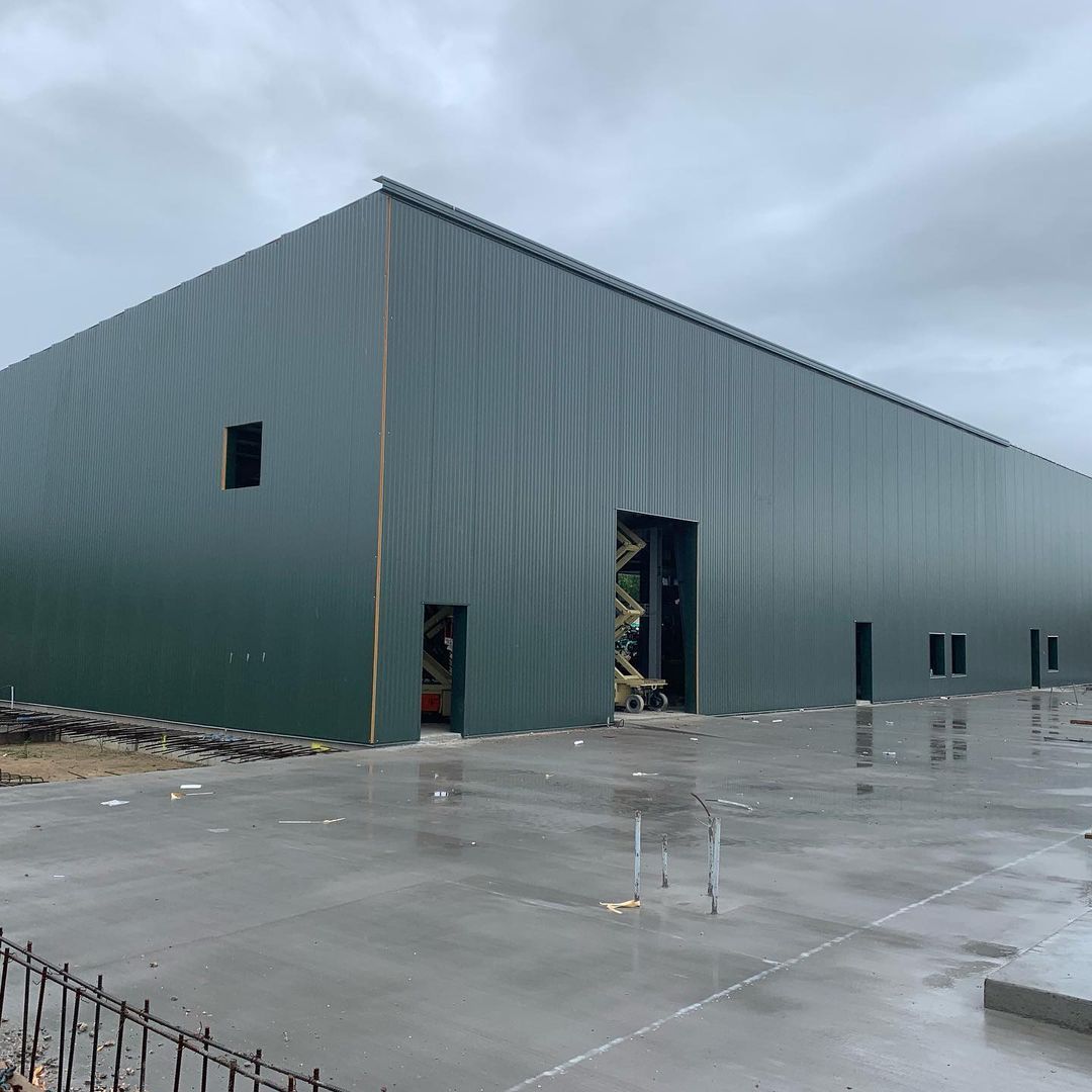 A large green building with a concrete driveway in front of it.
