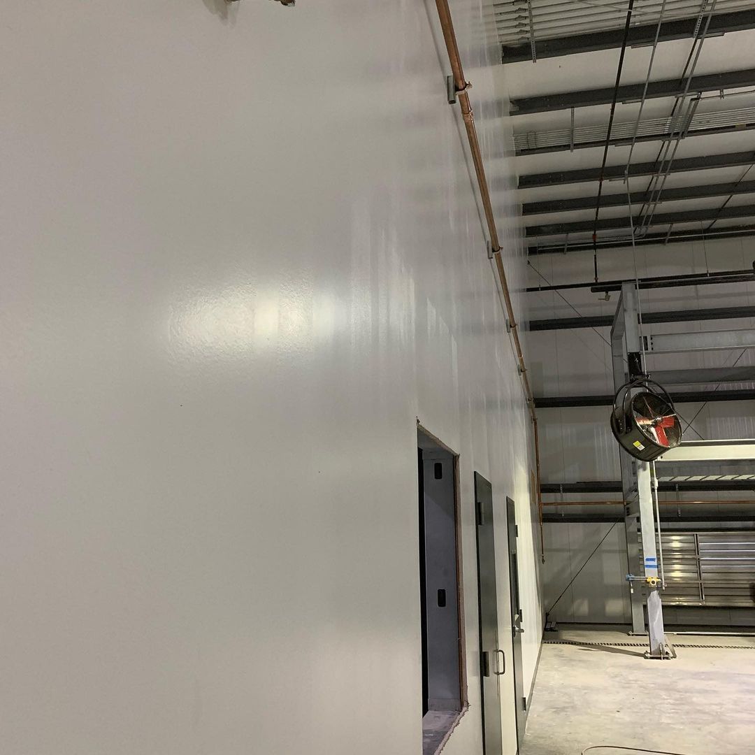 A large warehouse with white walls and a mirror on the wall.