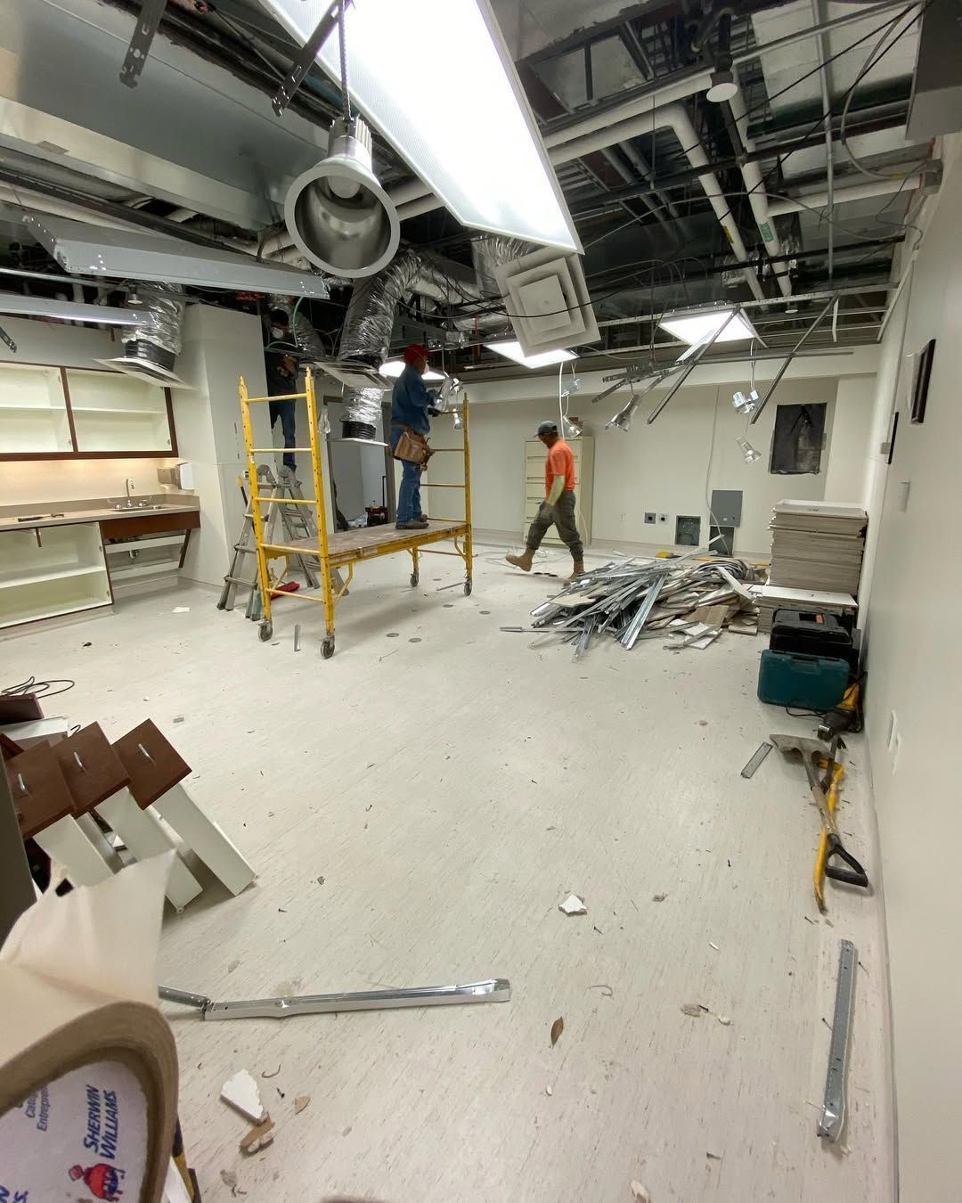 A man is standing on a scaffolding in an empty room.
