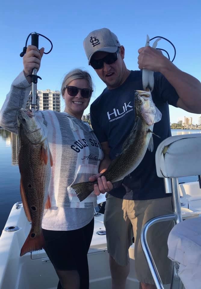 A man and a woman are holding two fish on a boat.