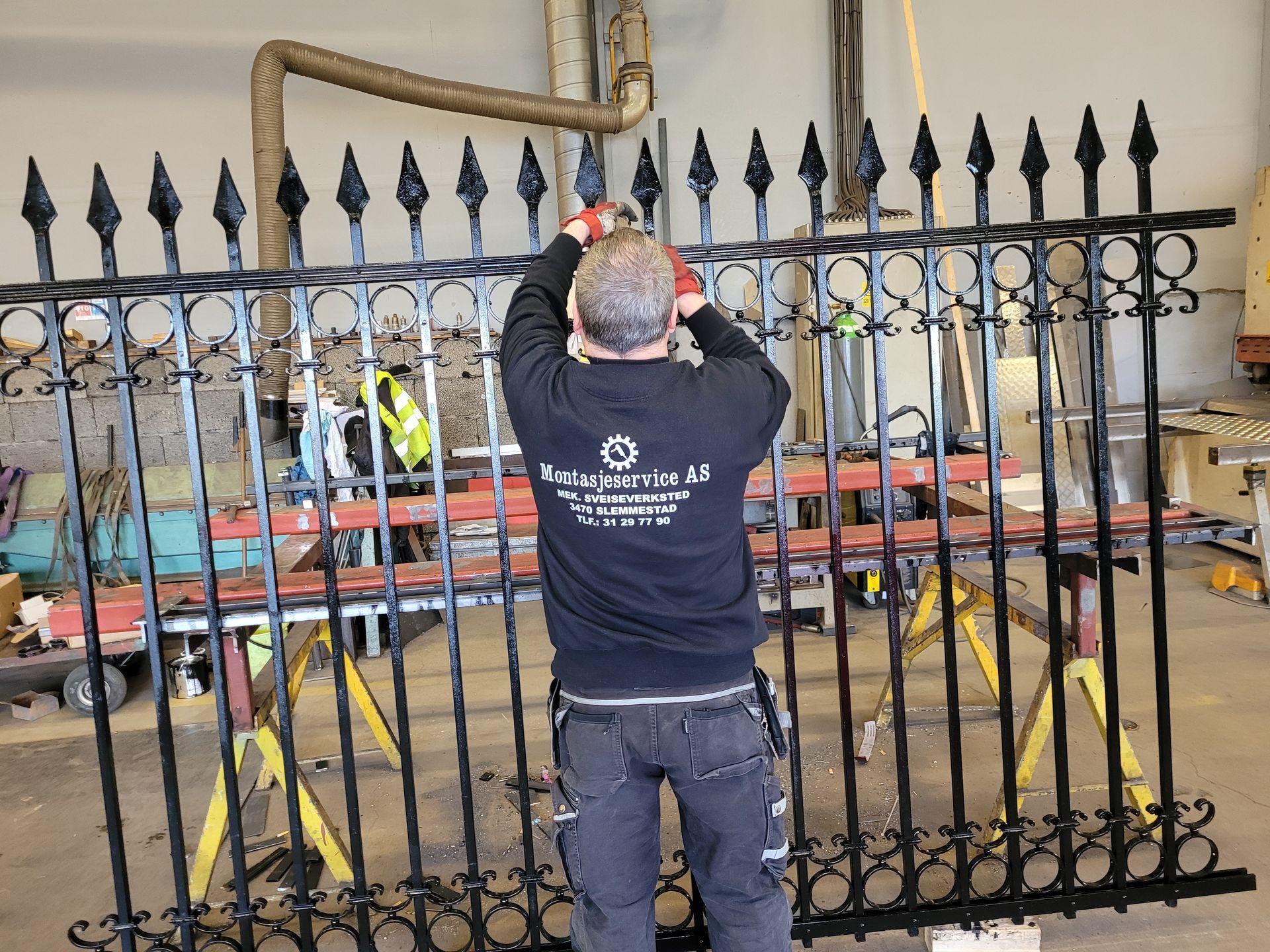 Mann som jobber med svart smijernsgjerde innendørs.
