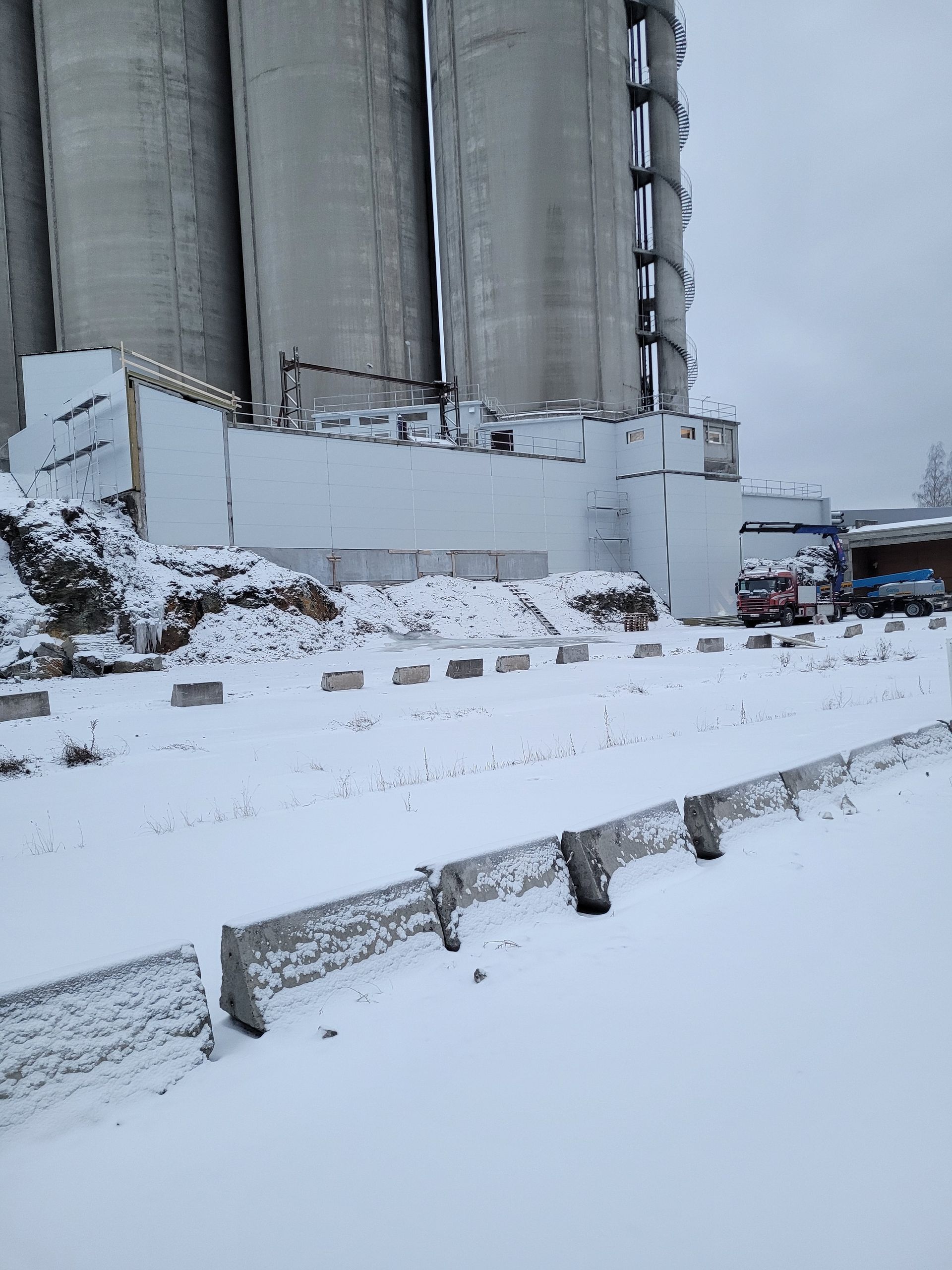 Snødekt landskap med industrisiloer. Bunnen av siloene har en delvis kollapset betongvegg.