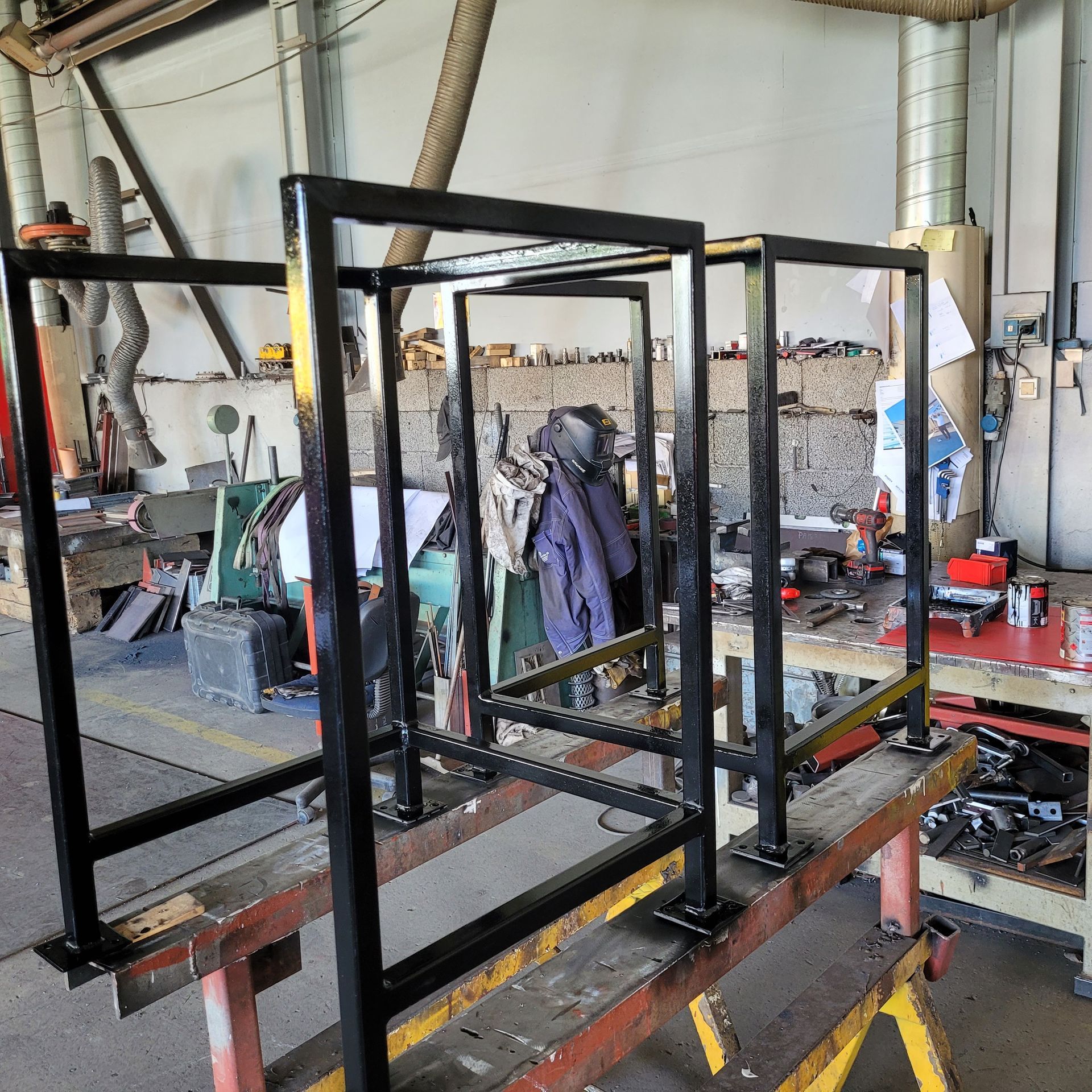 Svarte metallrammekonstruksjoner på en arbeidsbenk i et verksted.