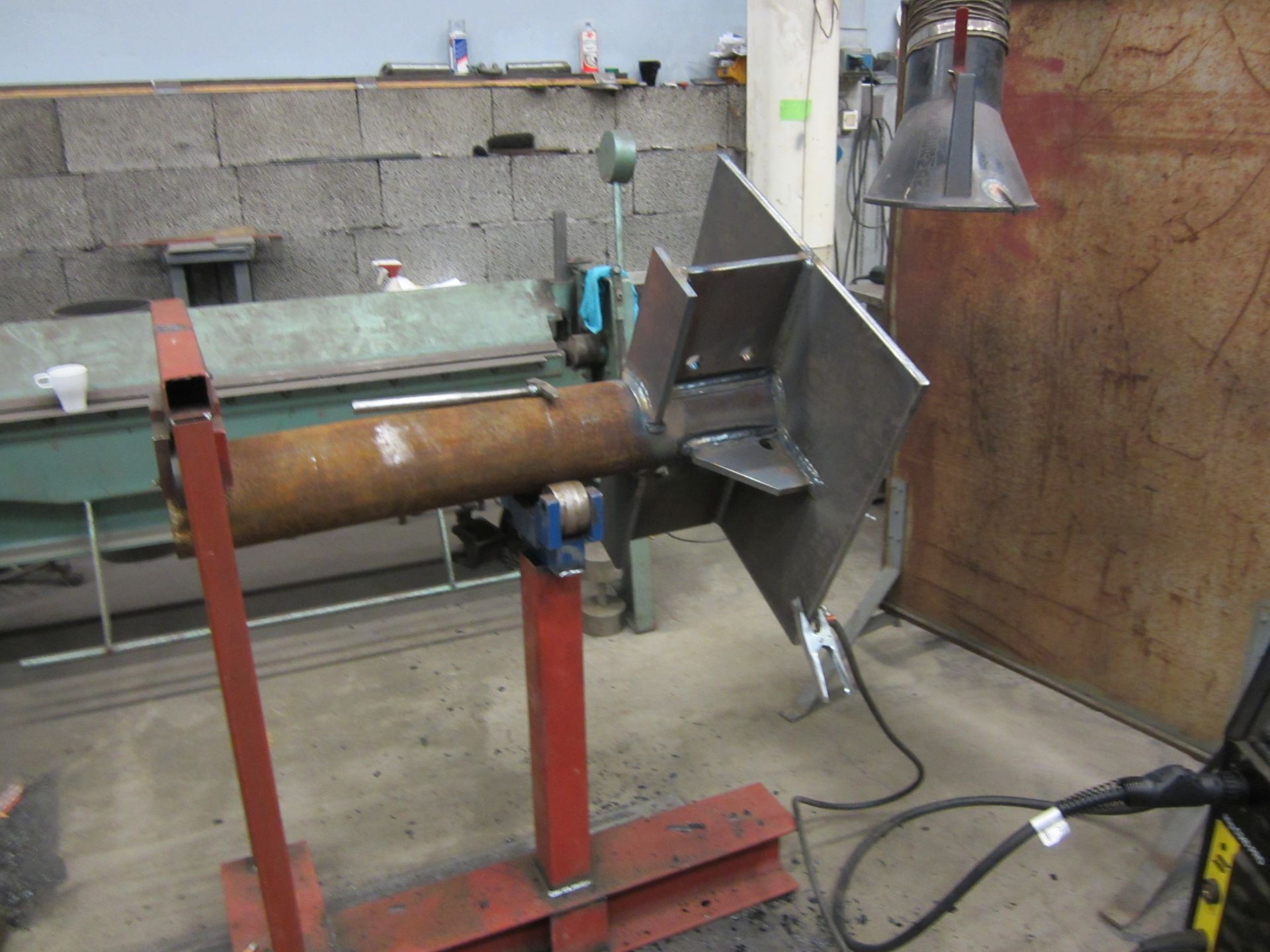 Sveiset metallfabrikasjon i et verksted; en roterende aksel med en firkantet plate og vinklede støtter.