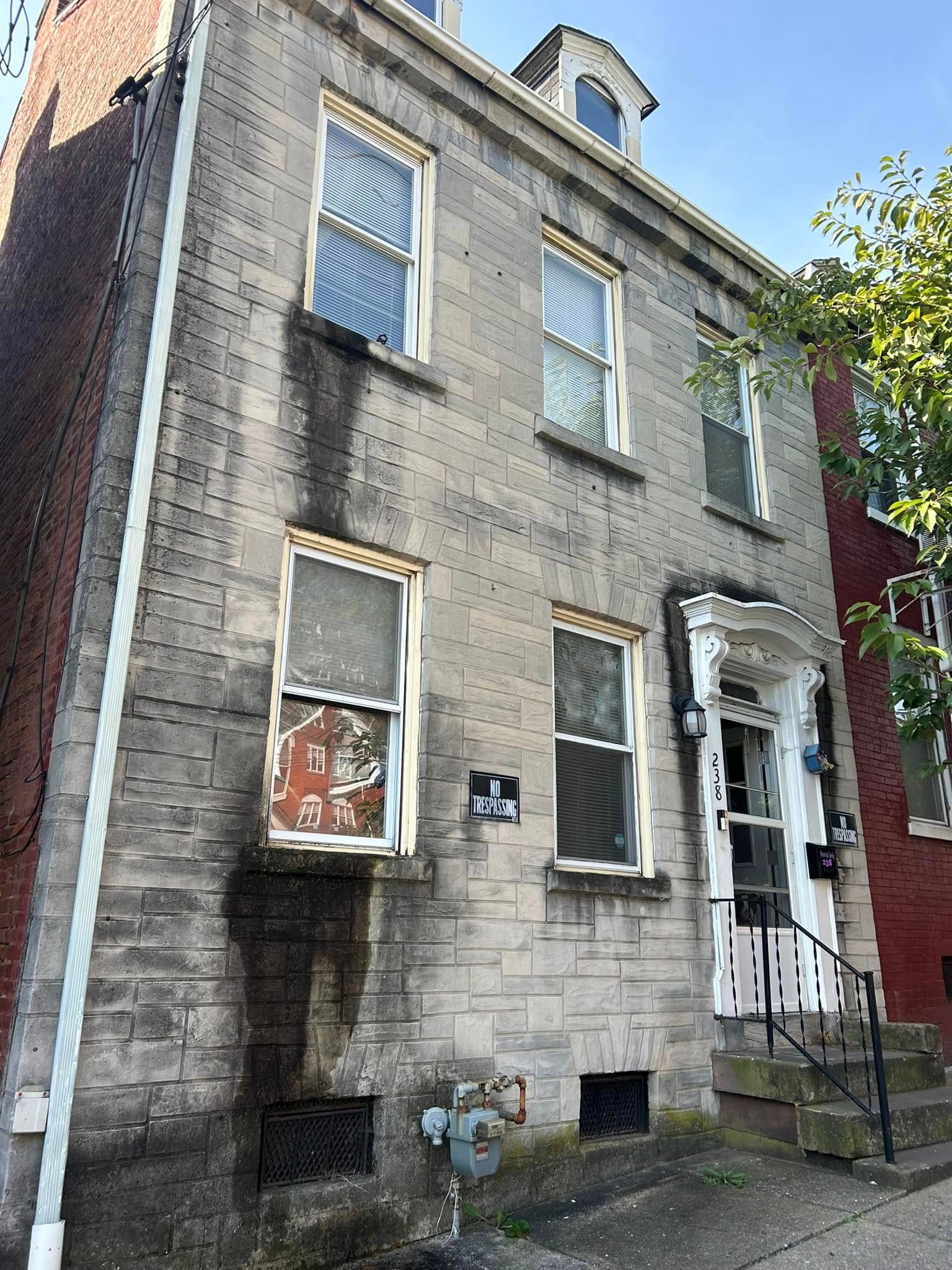 A weathered three-story stone building with several windows and a small front porch.