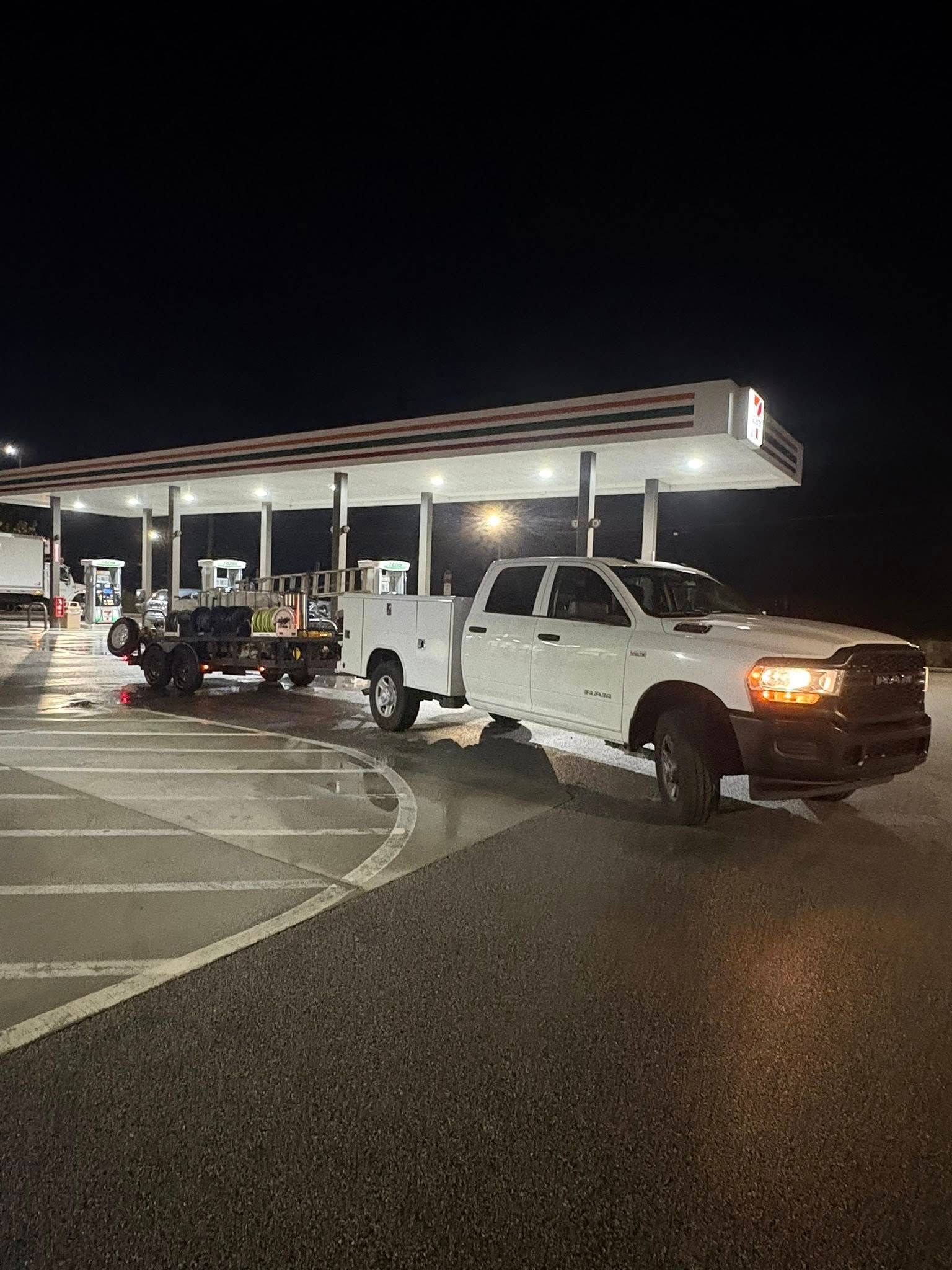 White work truck and trailer at a gas station at night.