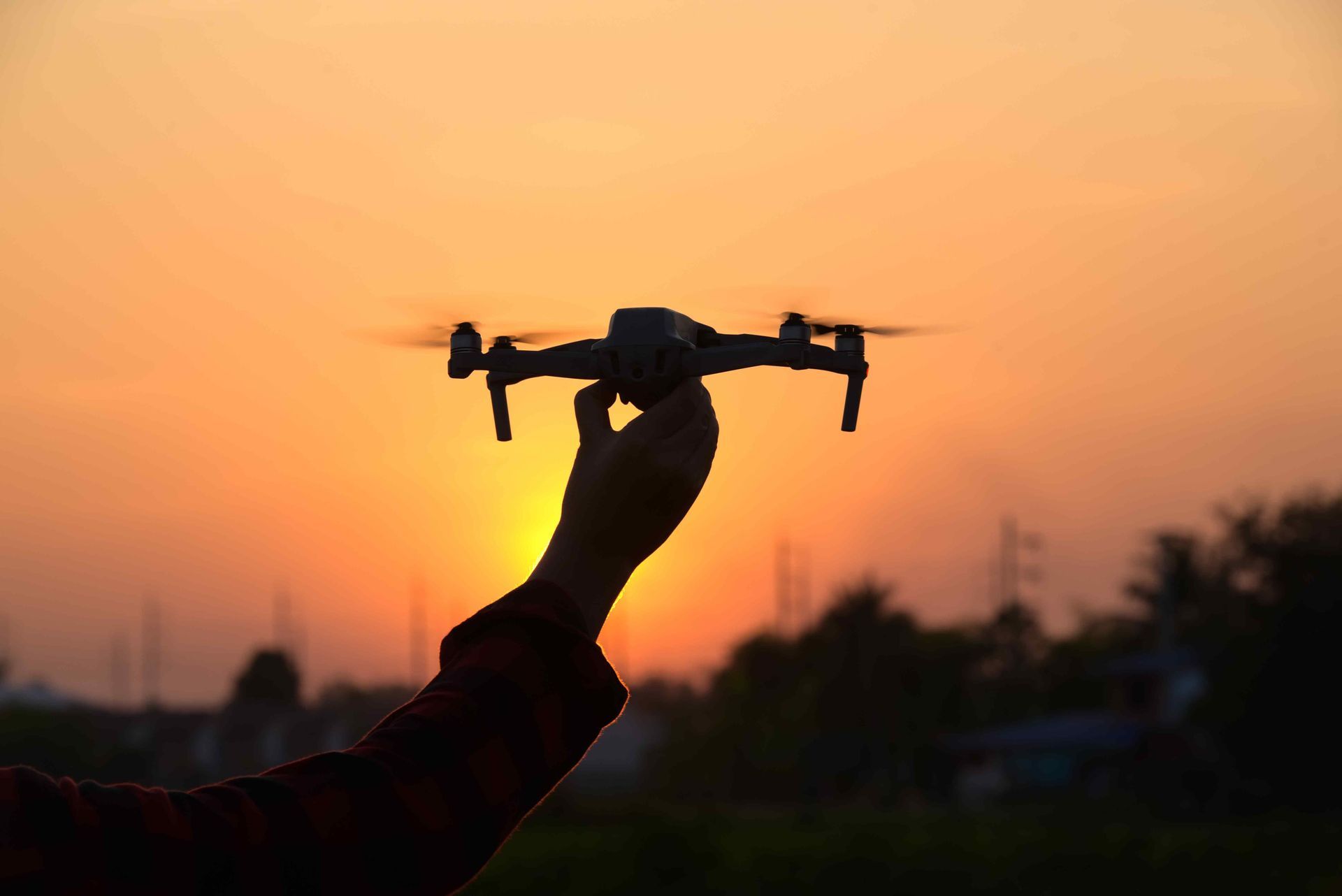 Sunset silhouette of a hand holding a drone