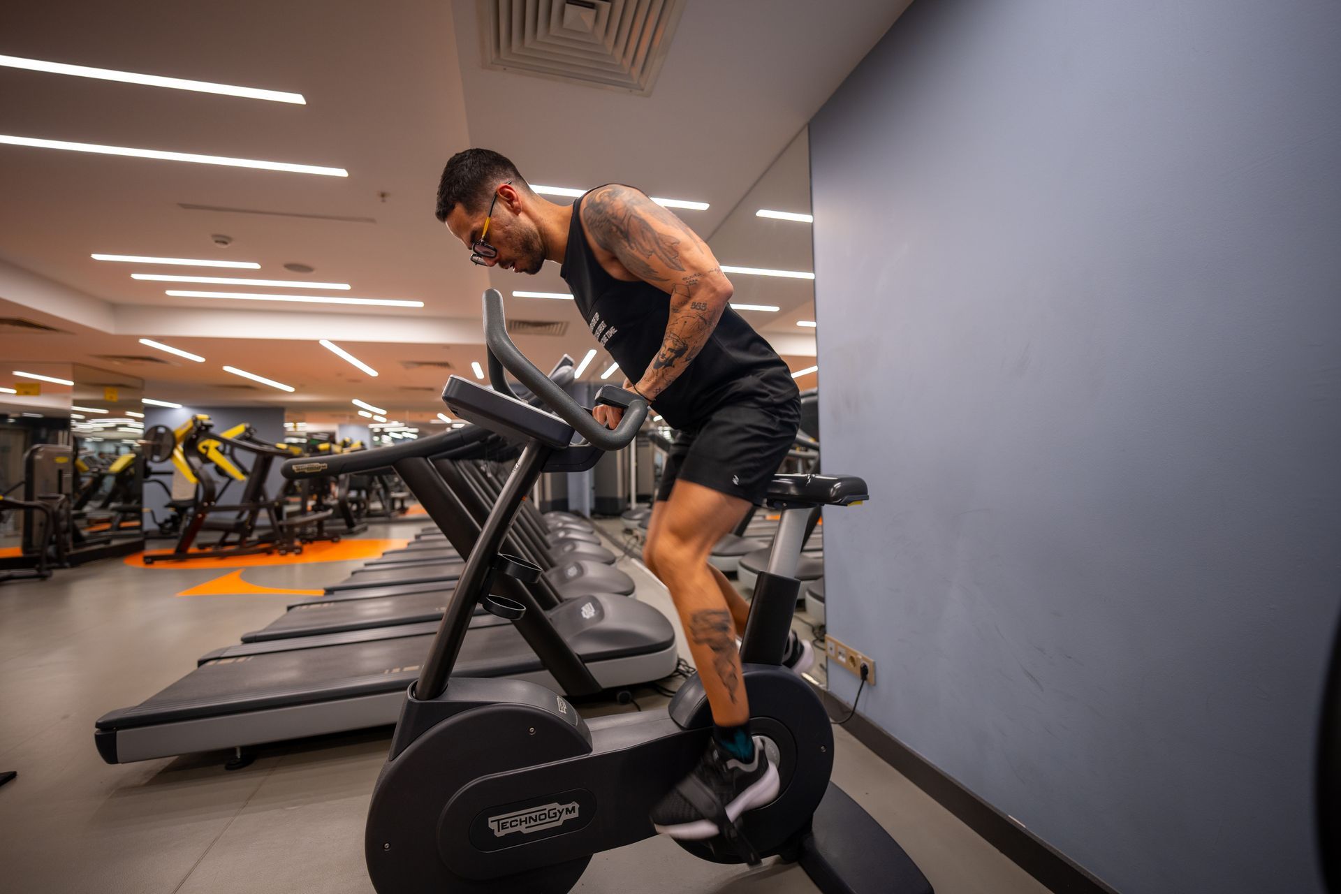 Bir kadın spor salonunda bir makinenin üzerinde oturuyor.