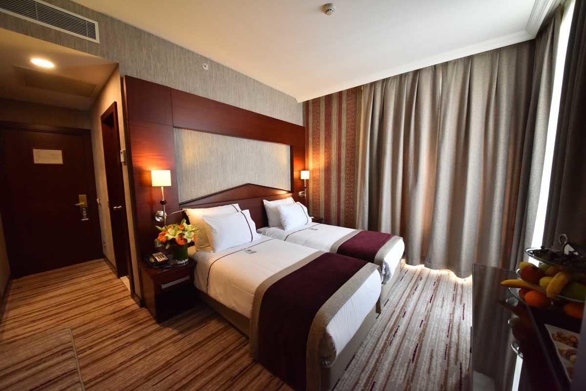 Iki yataklı ve pencereli bir otel odası.