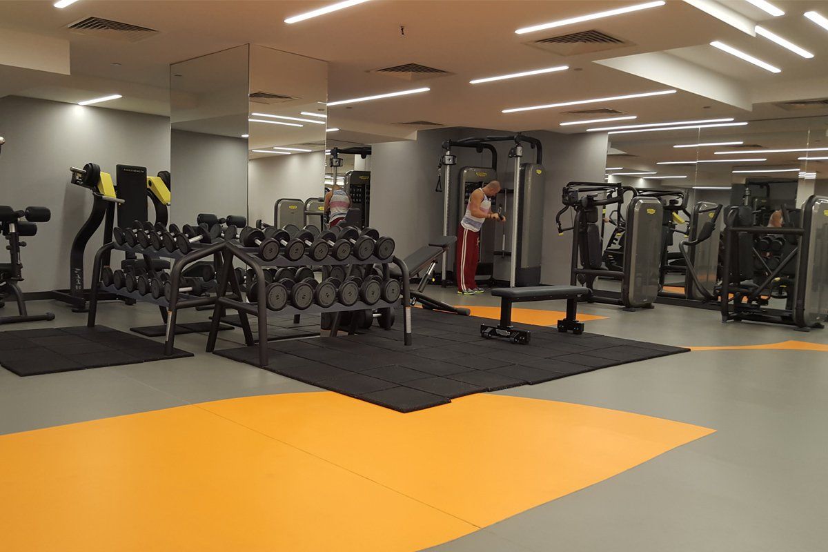 Bir kadın bir sürü dambılla spor salonunda duruyor.