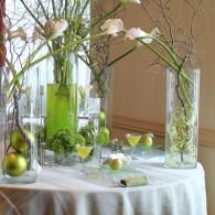 Green and clear glass vases with white flowers on a white tablecloth