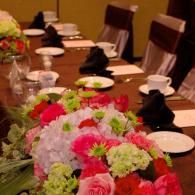Decorated dining table with floral centerpiece, plates, cups, and black napkins set for a formal event