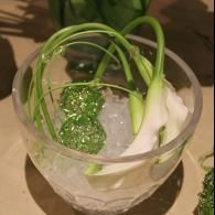 Clear bowl with ice, green garnish, and white vegetables on a table.