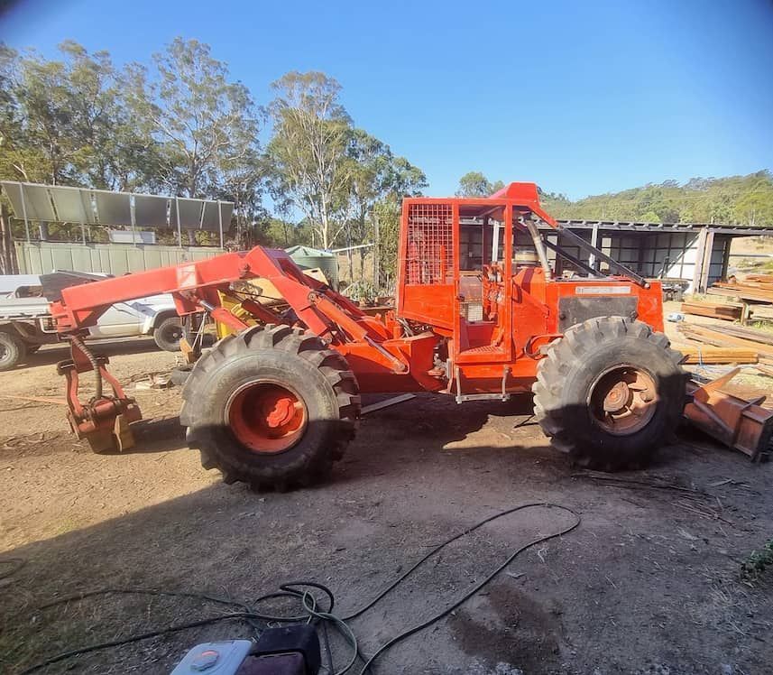 A Large Orange Tractor Is Parked In A Dirt Lot — Eungella Sawmill In Crediton, QLD