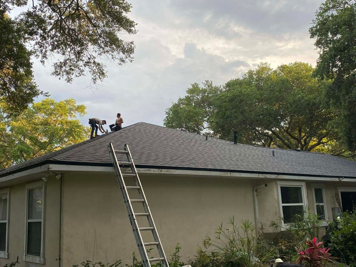 Two men are working on the roof of a house.