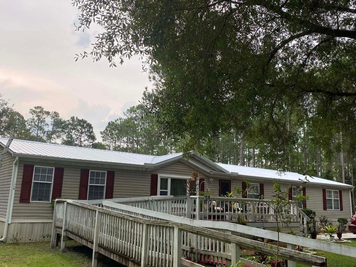 A mobile home with a ramp and trees in the background.