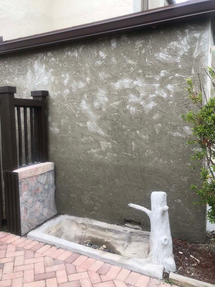 There is a tree stump in front of a wall.