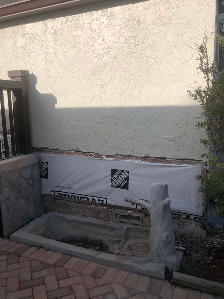 A stump is sitting in front of a house that is being remodeled.
