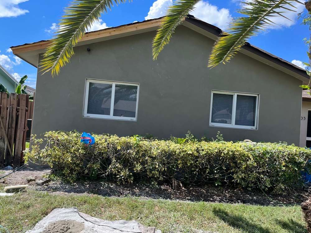 A house with a fence and a palm tree in front of it.