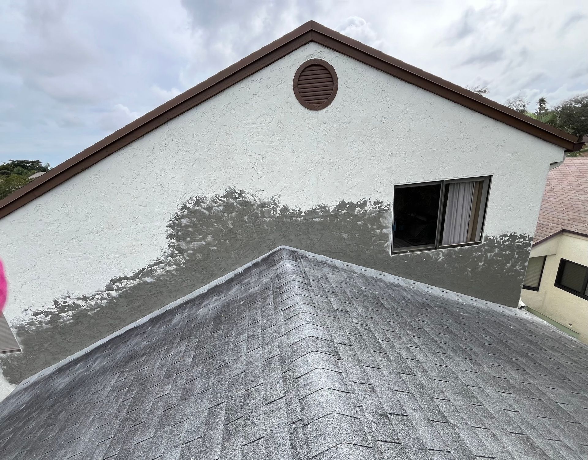 A white building with a brown roof and a window.