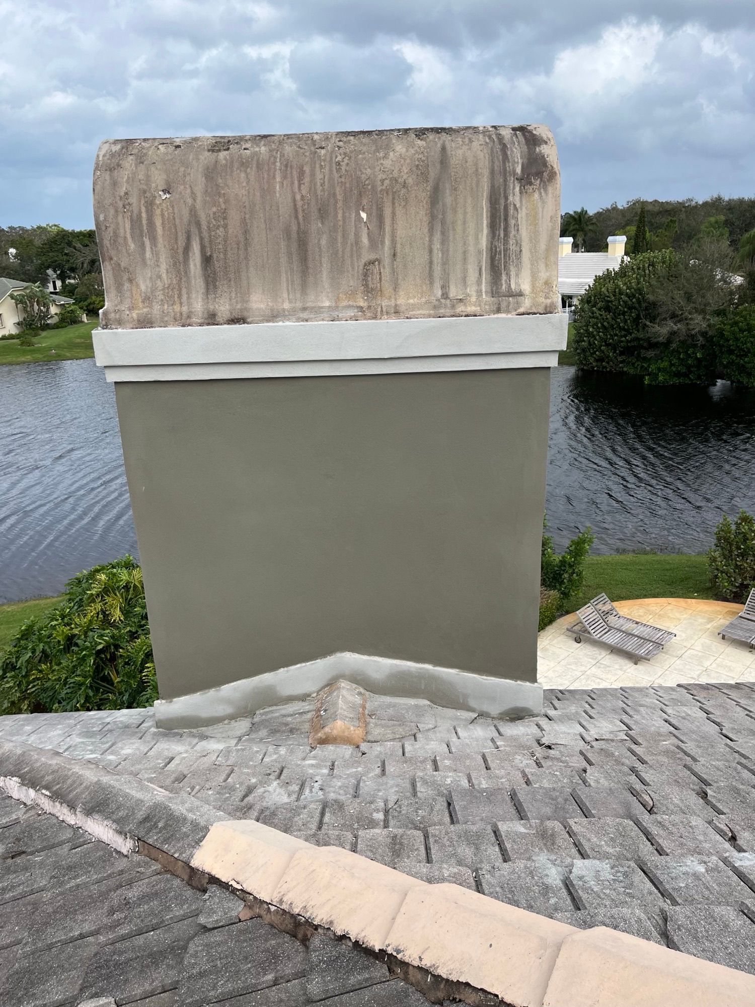 A chimney is sitting on top of a roof next to a body of water.