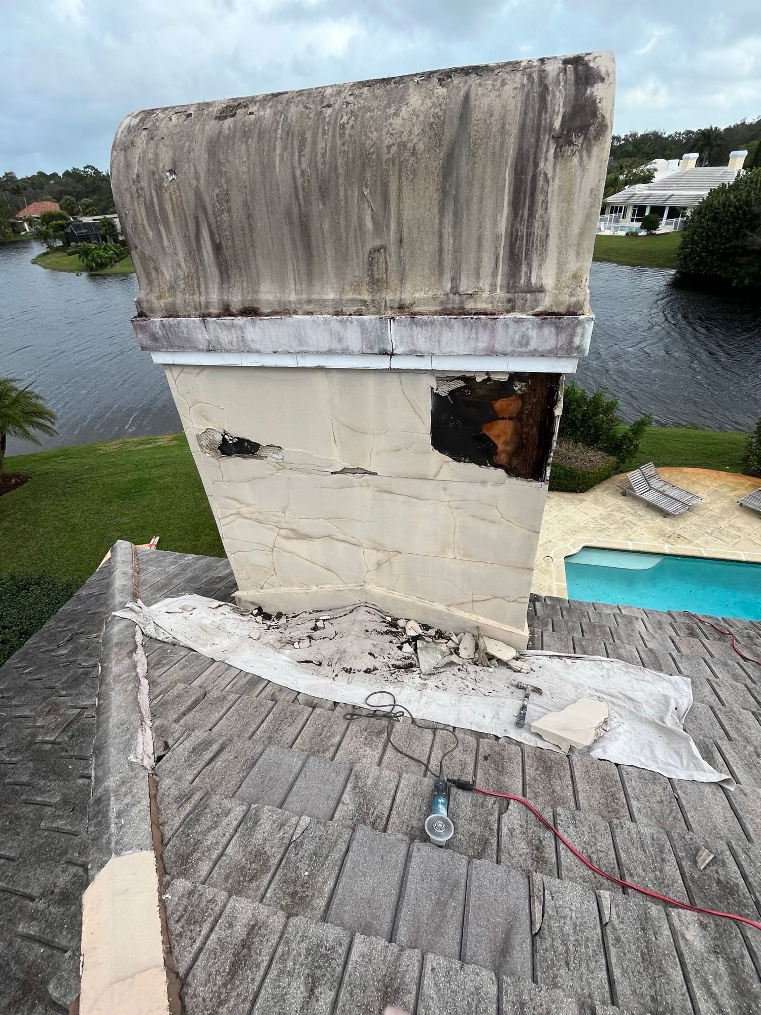 A chimney is sitting on top of a roof next to a pool.