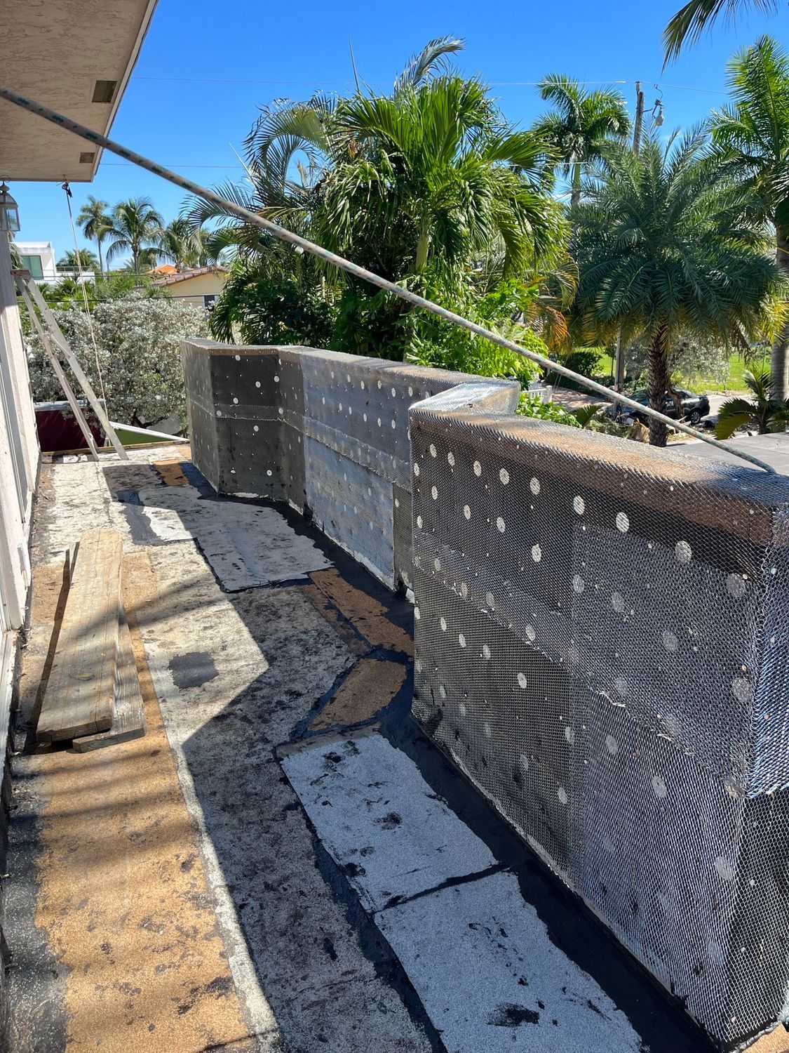 A balcony is being built on the side of a building with palm trees in the background.