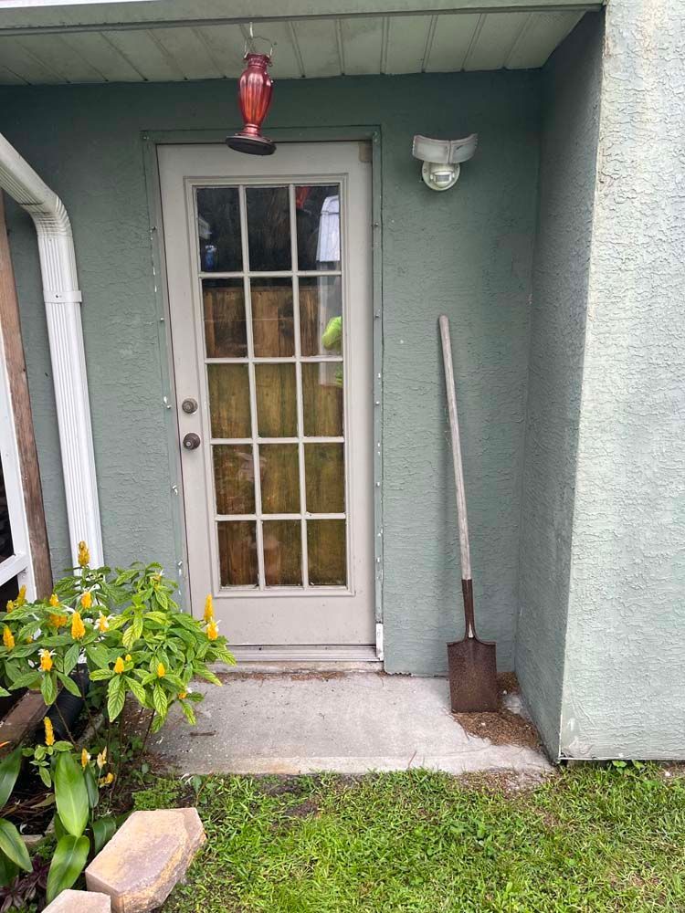 A shovel is sitting on the sidewalk in front of a door.