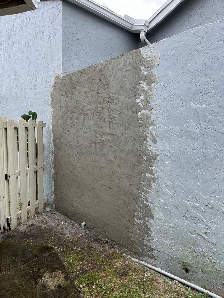 A fence is being painted on the side of a house.