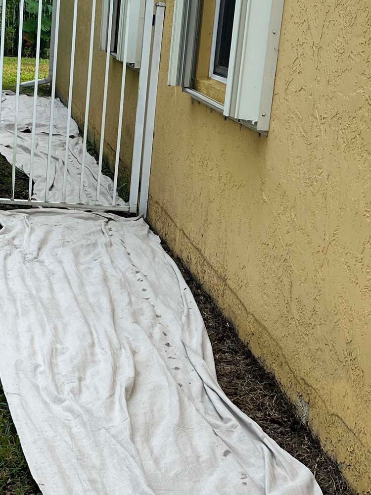 A white tarp is covering the side of a house.