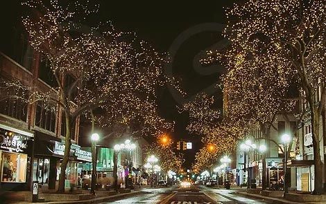 A city street is lit up with christmas lights at night.