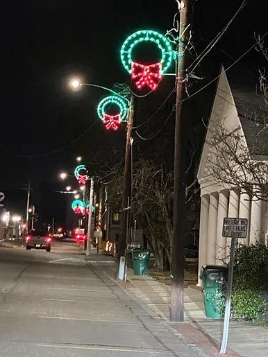 A street with christmas lights on the poles at night.