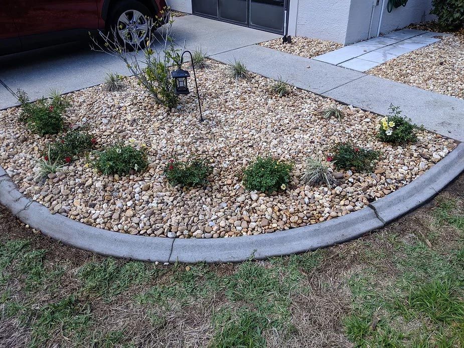 A car is parked in a driveway next to a gravel garden.