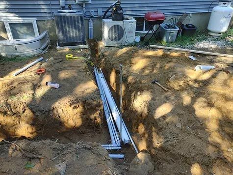 A ladder is sitting in the dirt next to a house.