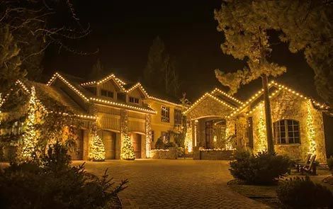 A large house is decorated with christmas lights at night.