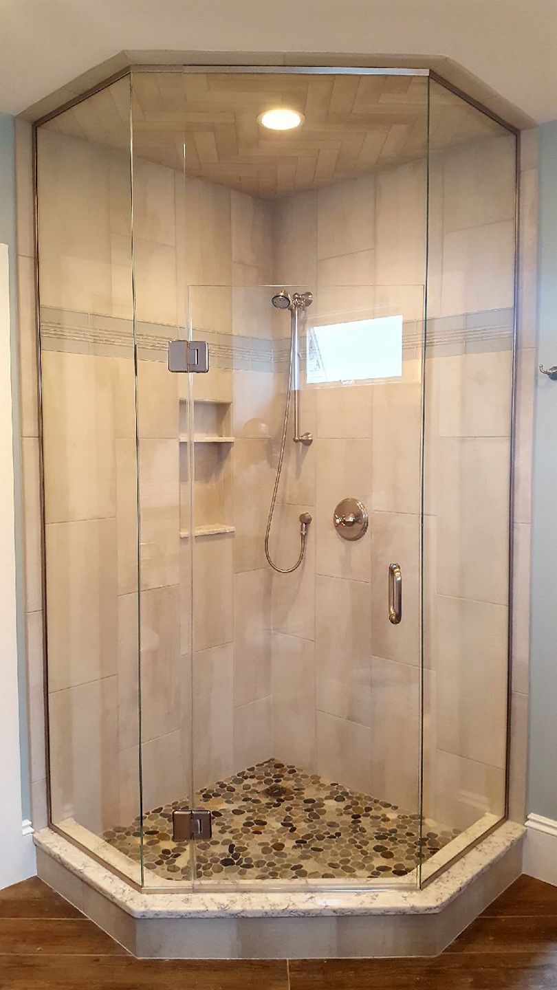 A shower stall with a glass door and a shower head in a bathroom.