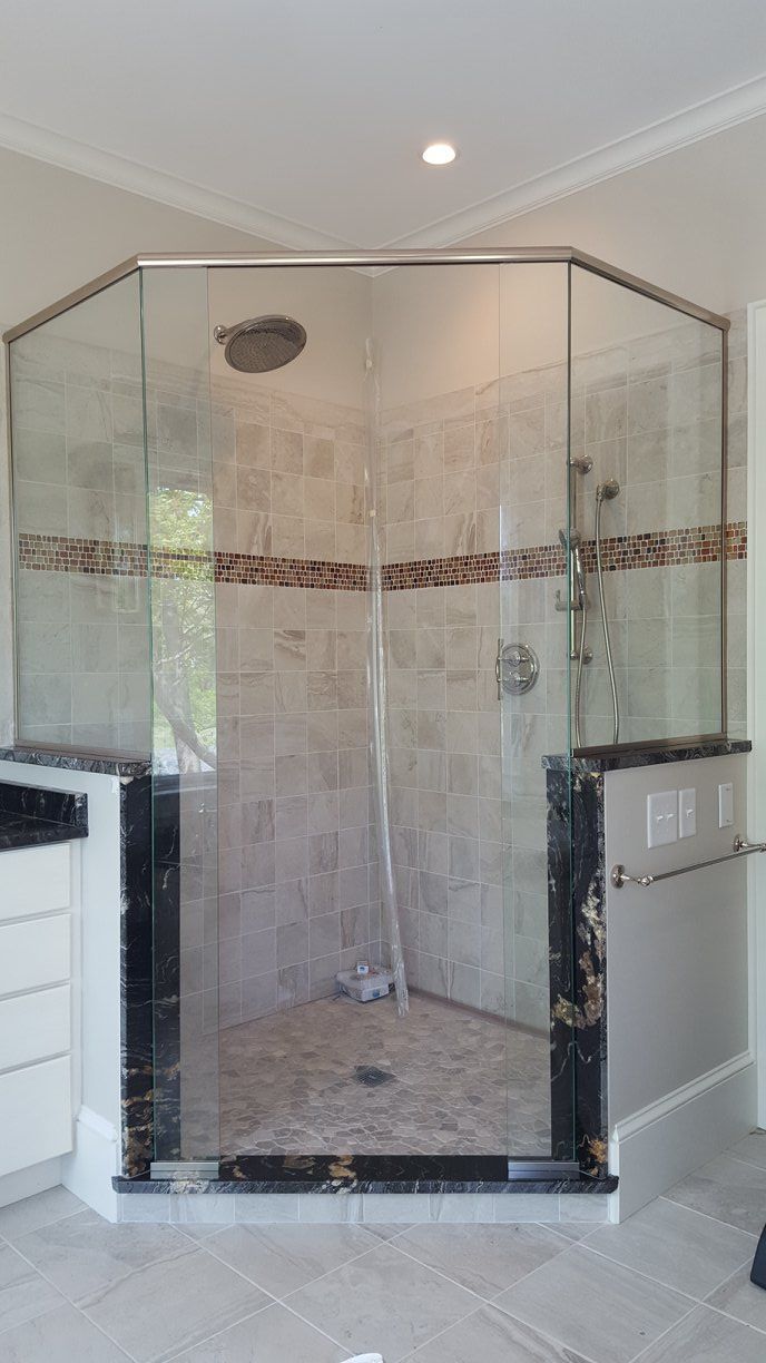 A bathroom with a walk in shower with a glass door.