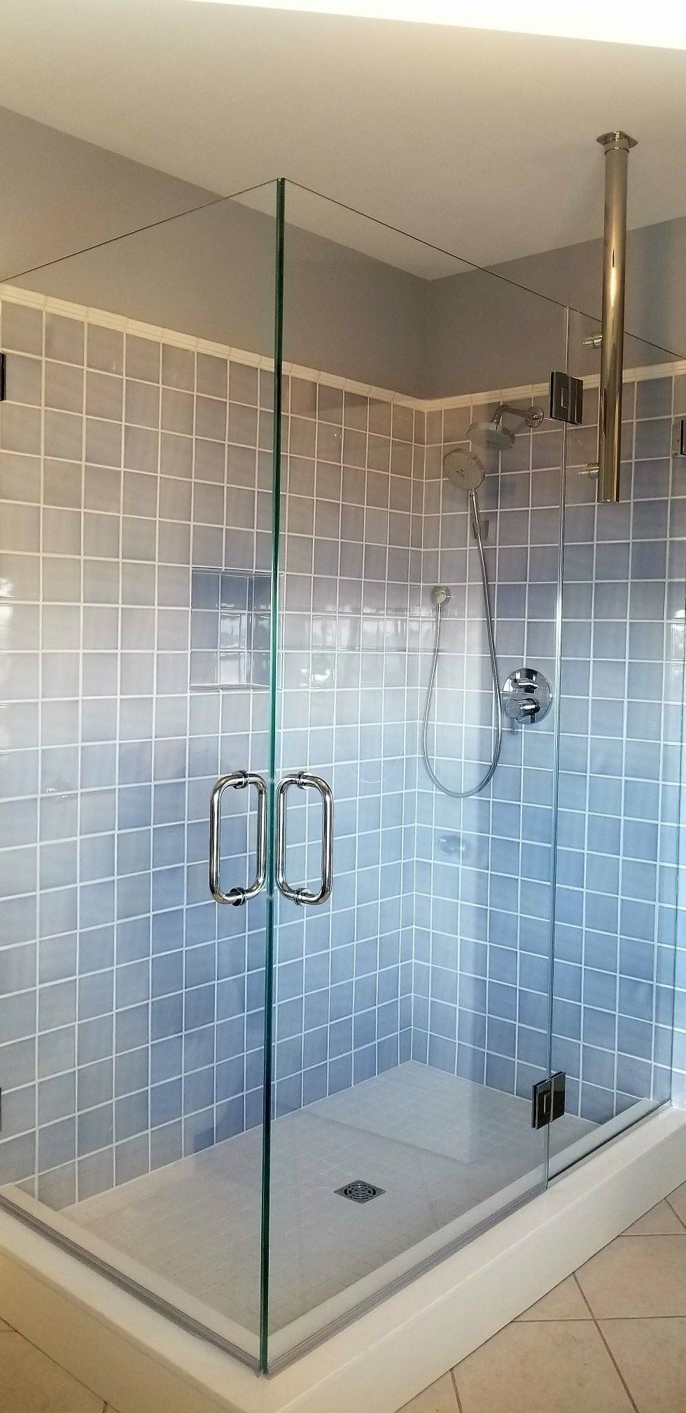 A shower stall with a glass door and a shower head in a bathroom.