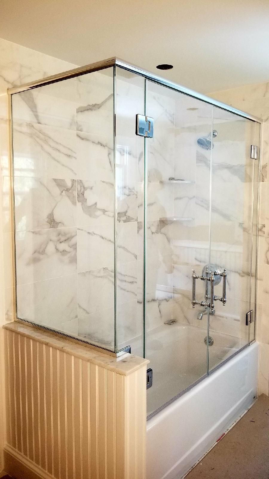 A bathroom with a bathtub and a glass shower door.