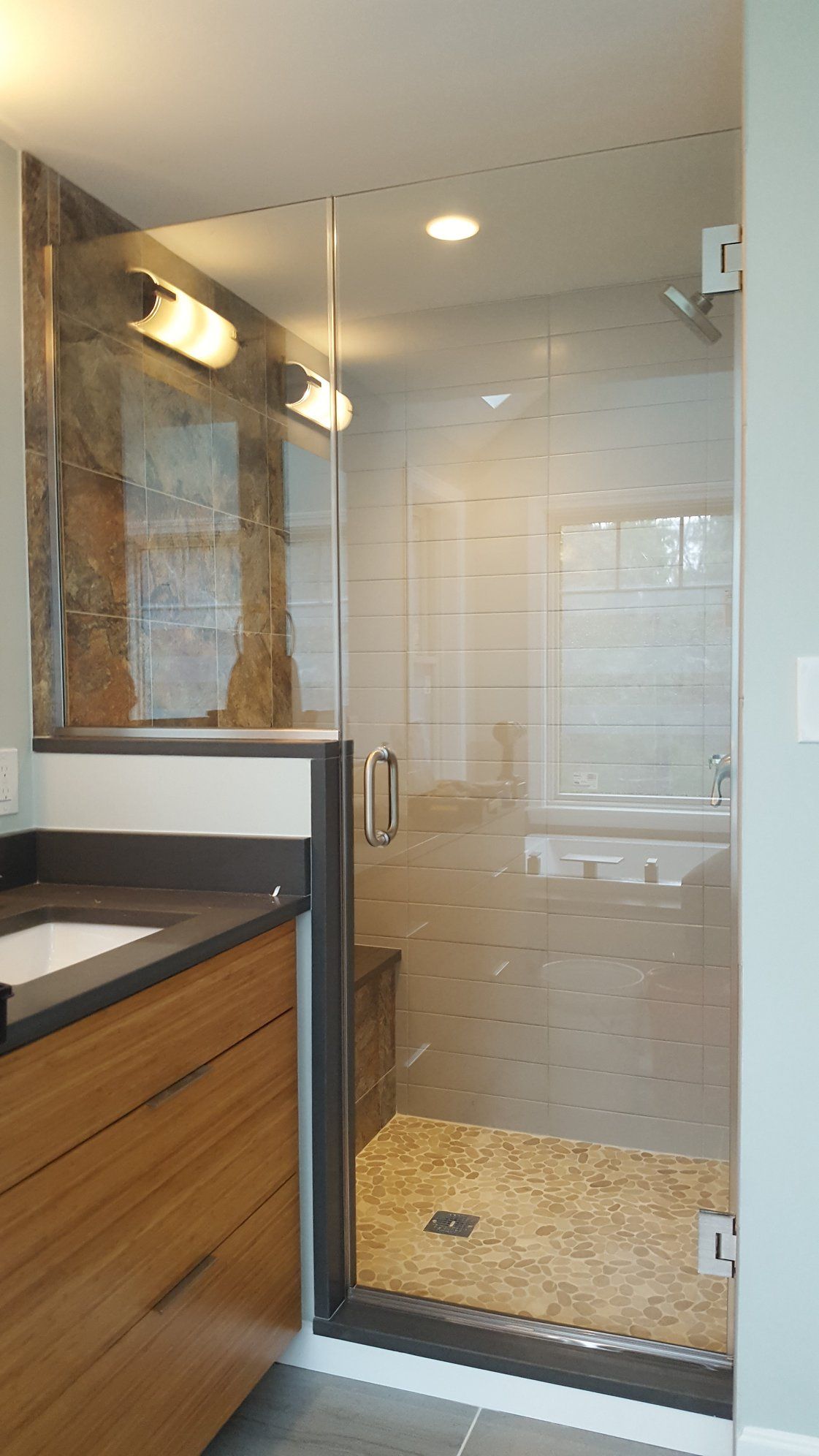 A bathroom with a walk in shower and a sink.