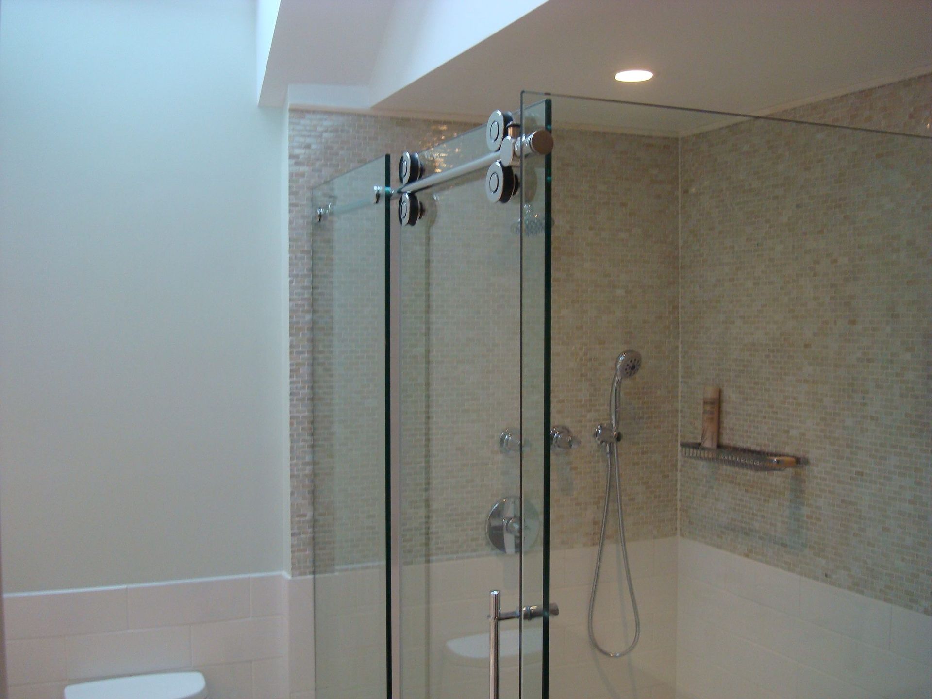 A bathroom with a sliding glass shower door and a toilet.