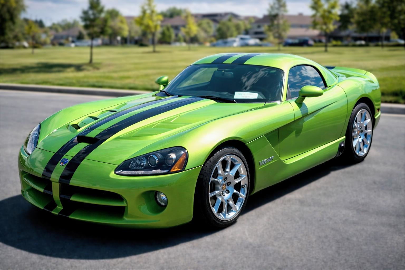 Green Dodge Viper sports car with black racing stripes parked on asphalt.