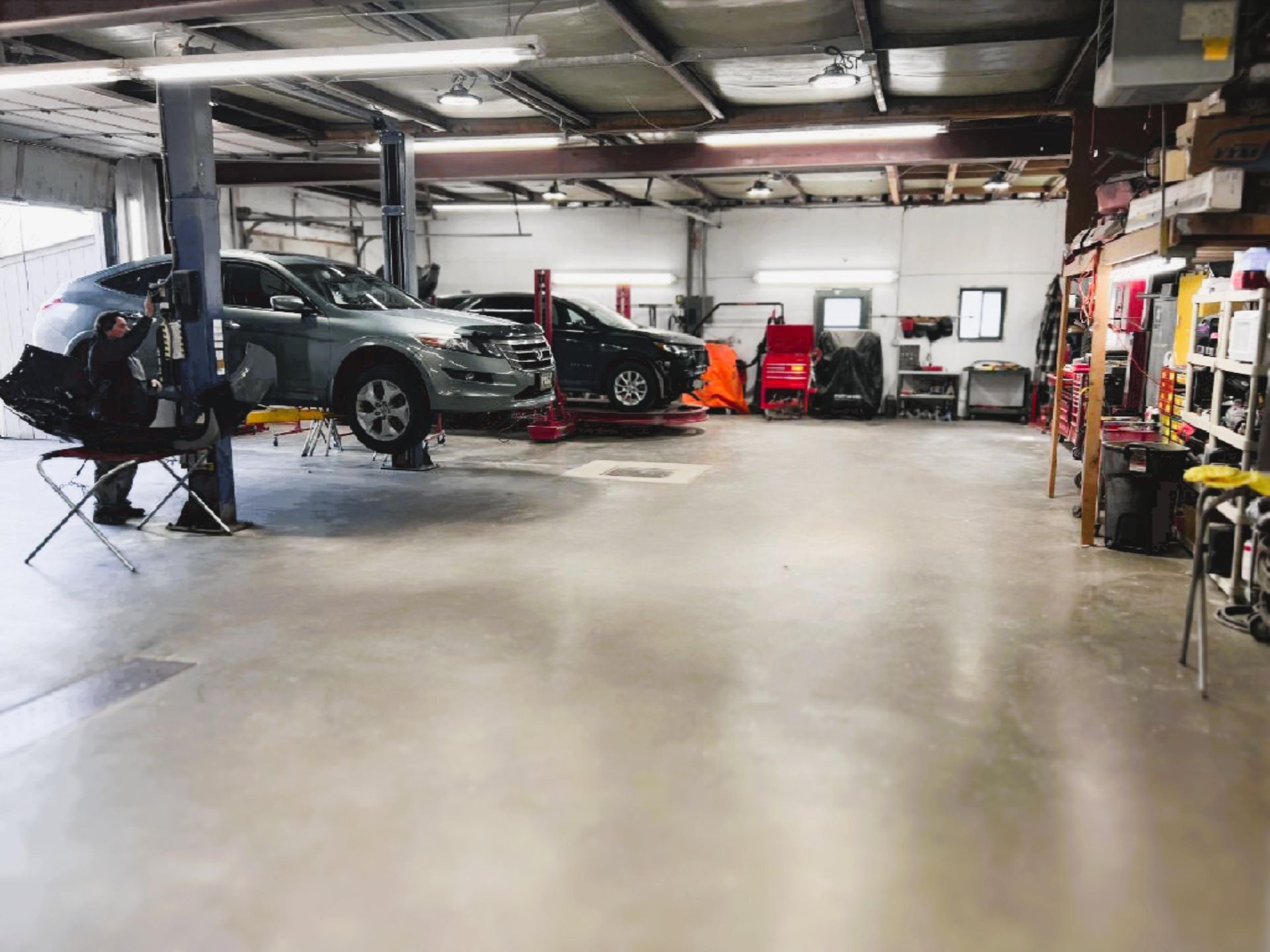 Interior of an auto repair shop, House of Color with cars on lifts, tools, and a concrete floor.